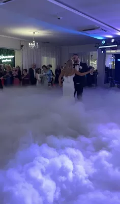 Para młoda tańczy pierwszy taniec w chmurach ciężkiego dymu na weselu w Lublinie.